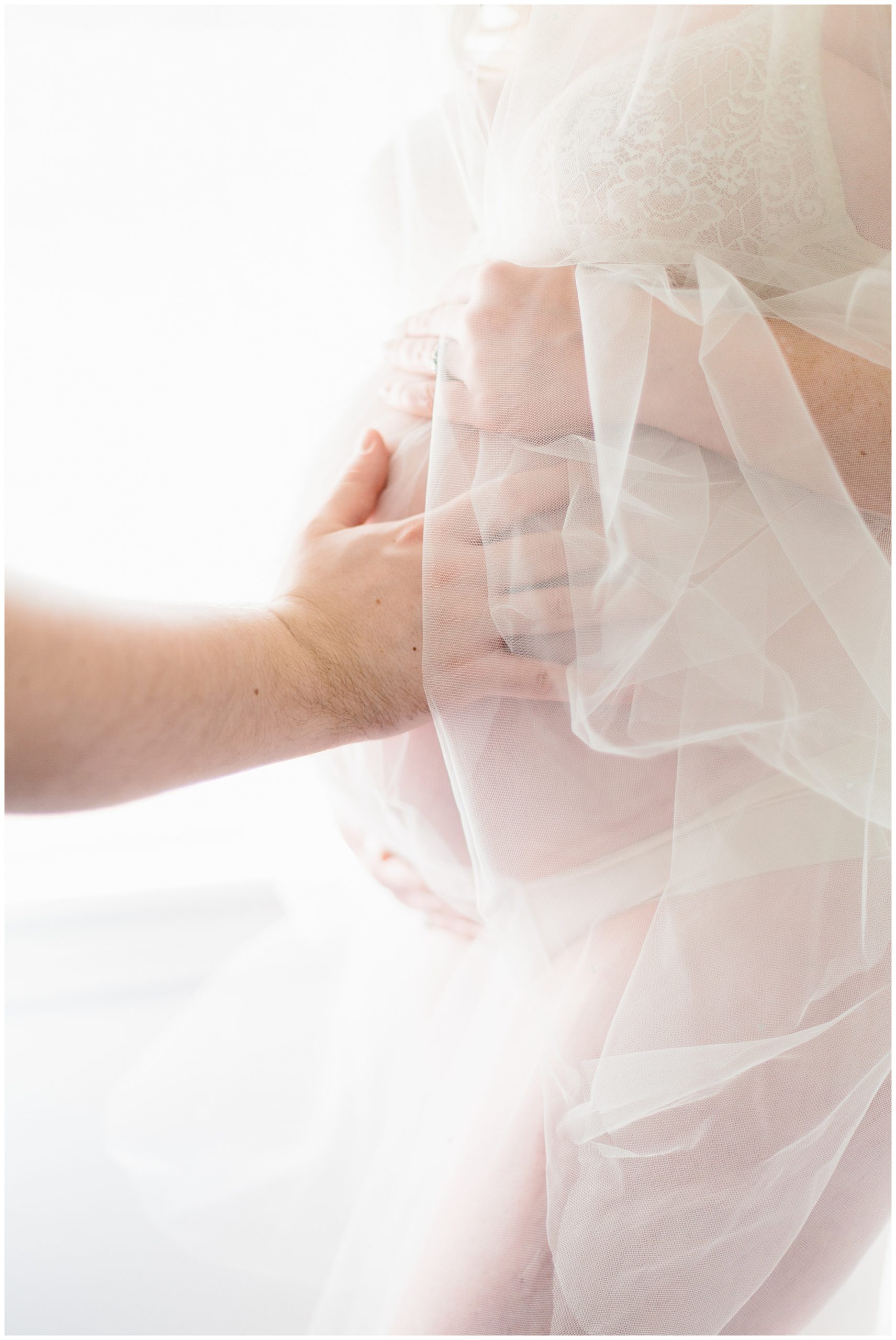 soft colors, maternity portrait of mother standing with lace, father's hand on belly