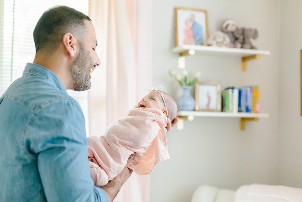 dad with newborn baby girl in light pink swaddle