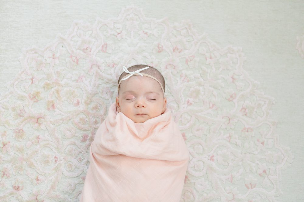 newborn baby girl in light pink swaddle